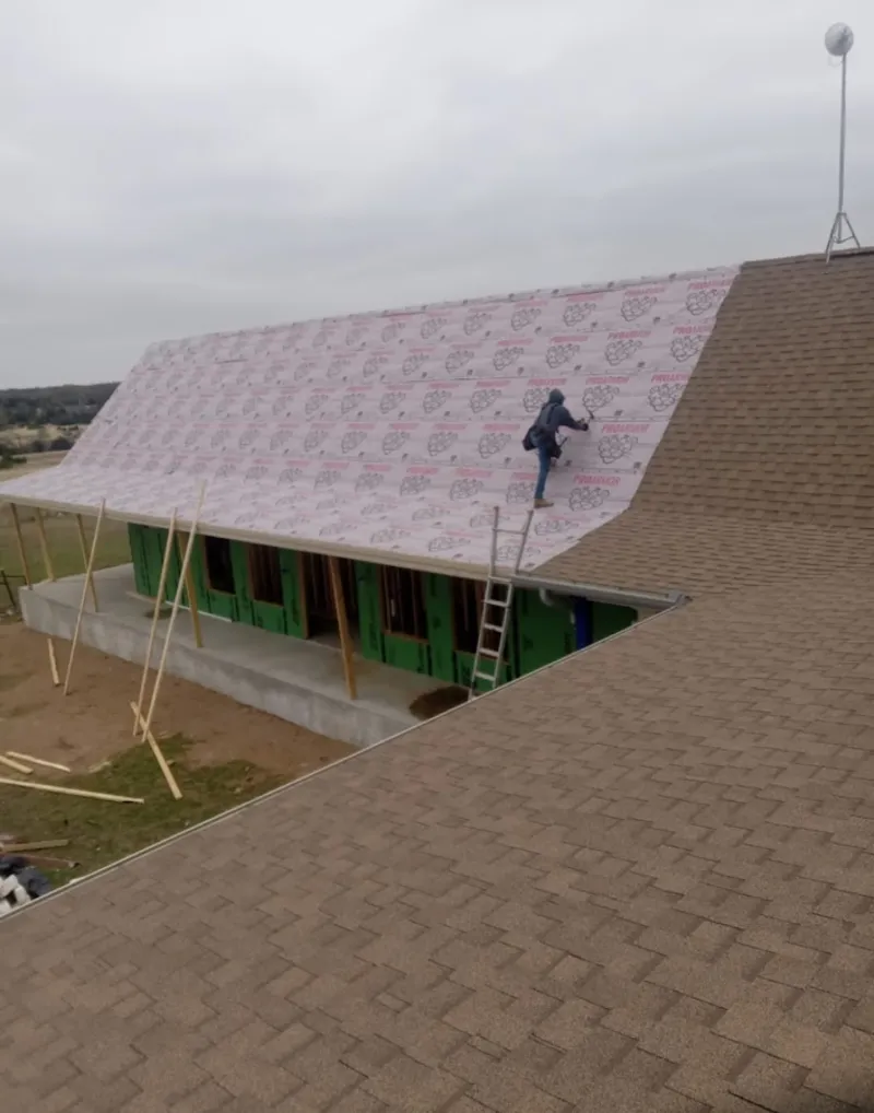Worker preparing underlayment for a metal roof installation in Corcoran